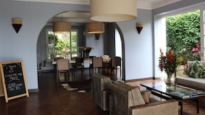 Una habitación amplia con comedor, sofá y mesa de centro. A la izquierda, una pizarra con texto.