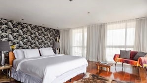 Un dormitorio moderno con una cama grande, un sofá y una pared estampada.
