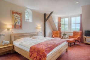 Een hotelkamer met een groot bed, twee stoelen, een televisie en een schilderij aan de muur.
