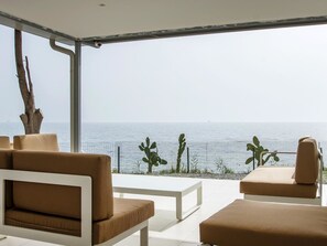 A modern outdoor seating area with a view of the sea, featuring a white table and two beige sofas. - B&B Do'mmilio (Crotone)