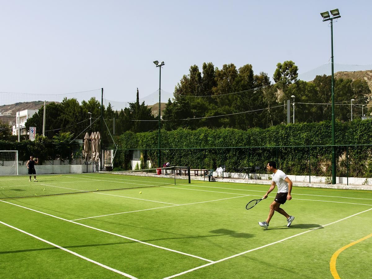 Ein Tennisplatz mit Netz, zwei Spielern und einem Fangzaun.
