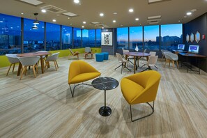 Un espace de bureau moderne doté de grandes fenêtres, de plusieurs types d’aménagements pour s’asseoir et offrant une vue sur la ville.
