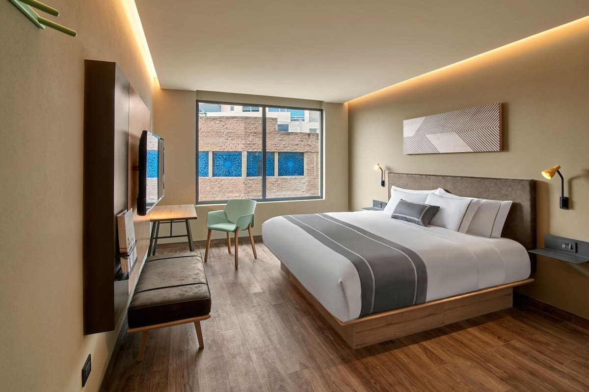 Una habitación de hotel moderna con una cama grande, un escritorio, una silla y un televisor.