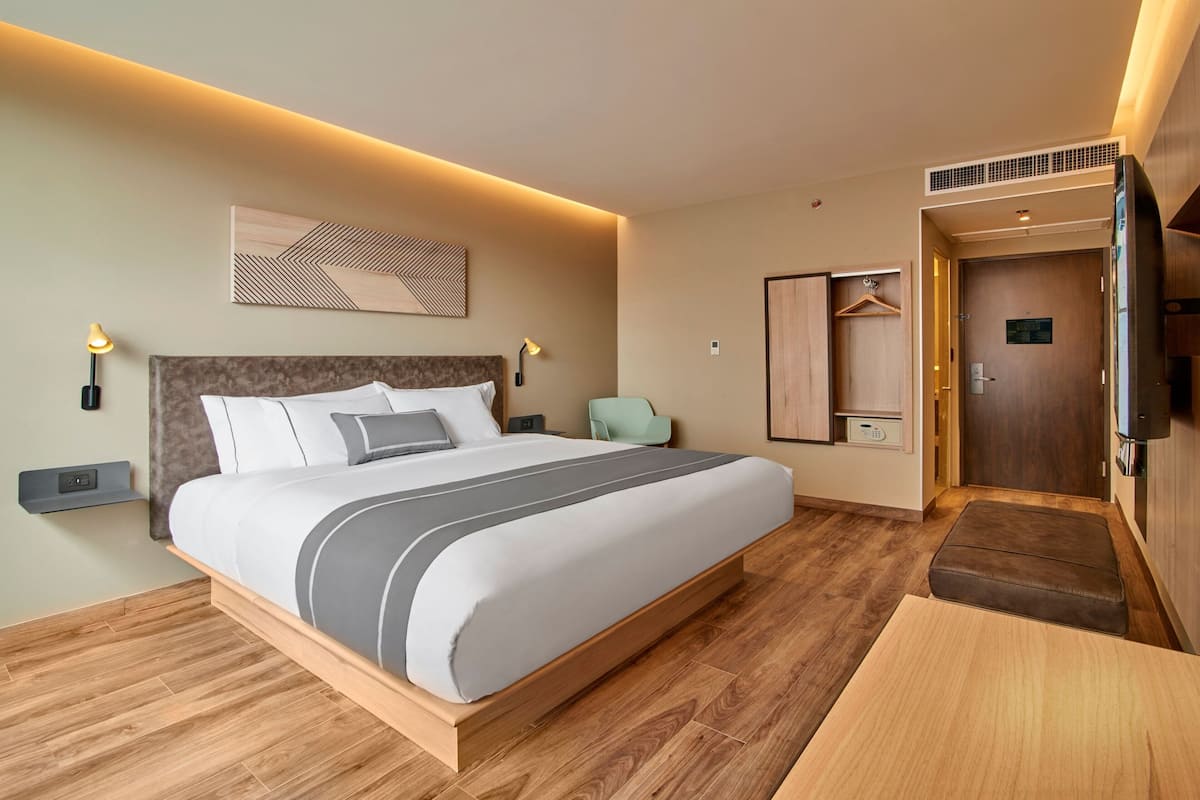 Una habitación de hotel moderna con una cama grande, mesitas de noche, un televisor y un armario.