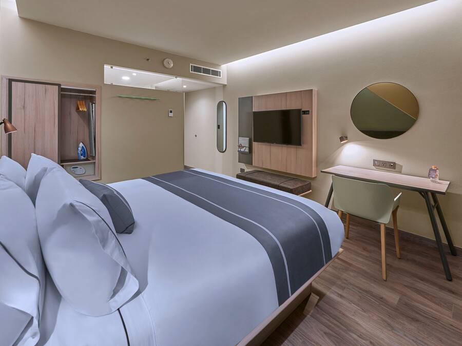 Une chambre d’hôtel moderne équipée d’un grand lit, d’un bureau, d’une télévision et d’une armoire.