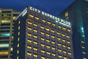 Un edificio de varios pisos con señalización iluminada que dice 'CITY EXPRESS PLUS BY MARRIOTT'.