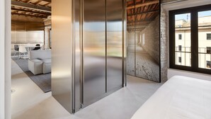 A modern room with a large sliding door, a dining area with a table and chairs, and a view of the city through a window. - Rhinoceros (Rome)