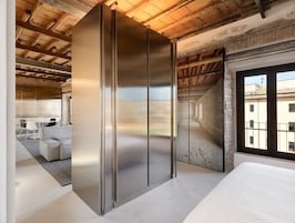 A modern room with a large sliding door, a dining area with a table and chairs, and a view of the city through a window.