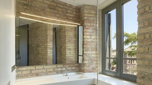 A bathroom with a white sink, a large mirror, and a brick wall. - Rhinoceros (Rome)