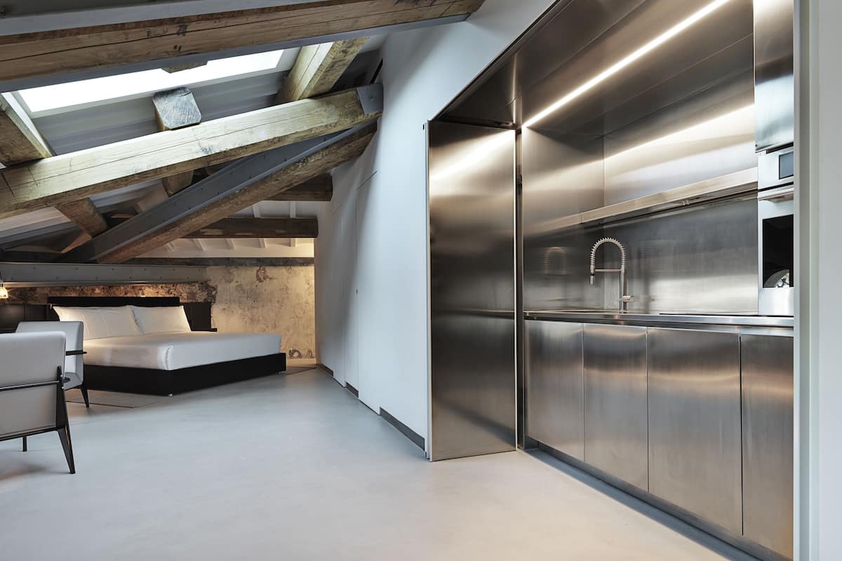 A modern kitchen with stainless steel appliances, a skylight, and exposed wooden beams.