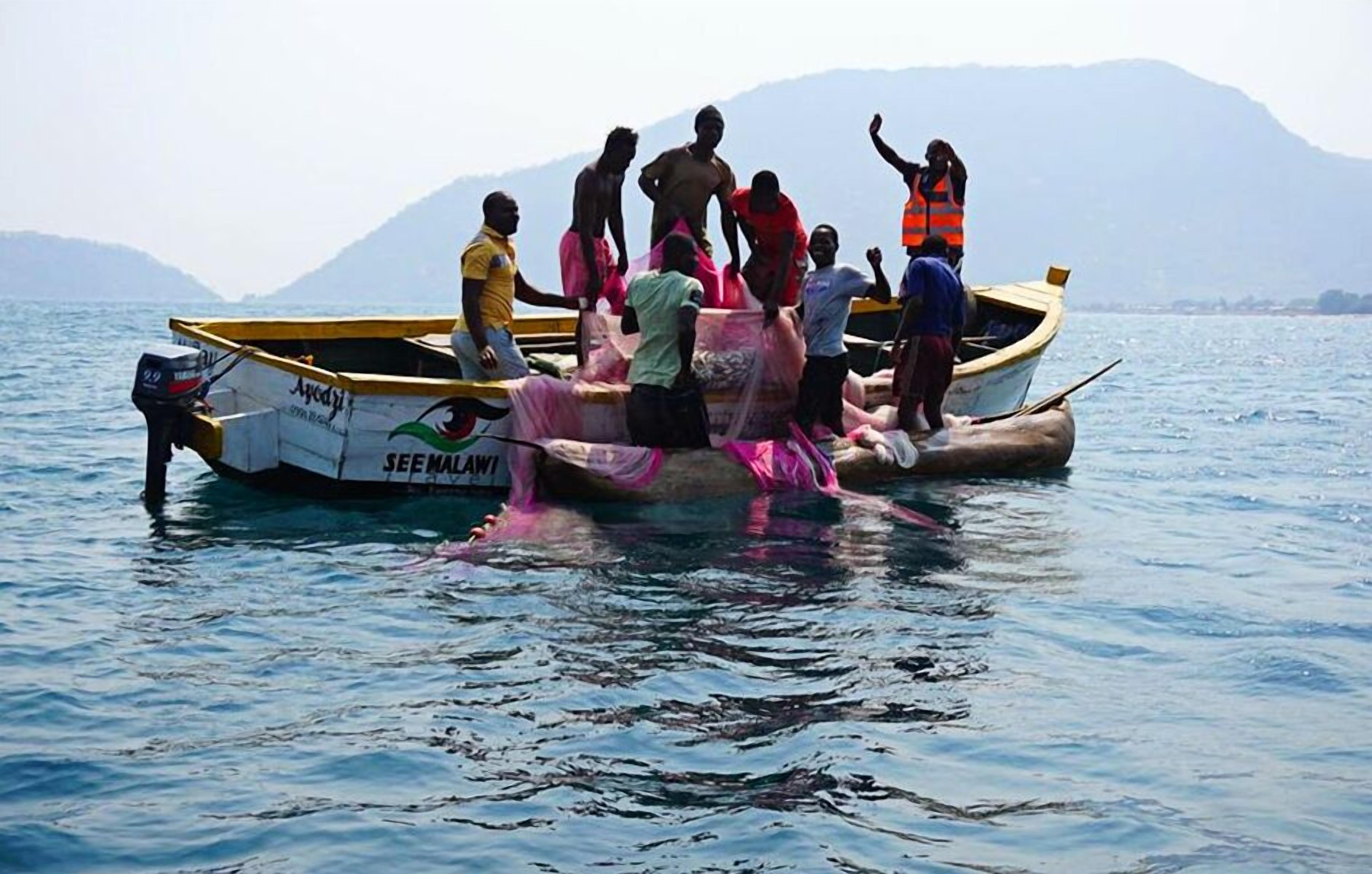Un grupo de personas en un bote frente a un paisaje montañoso.