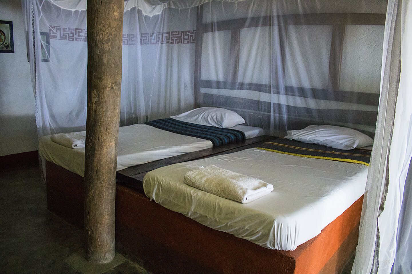 A room with two beds, each with a canopy and a pillow.