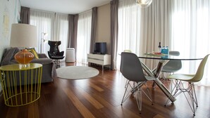 A modern living room with a sofa, a coffee table, a dining table with chairs, a television, and a lamp. - Cardosas Story Apart byPortoCityHosts (Porto)