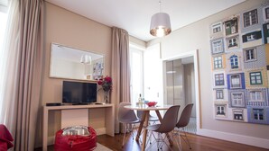 A modern living room with a TV, dining table, chairs, and a red bean bag. - Cardosas Story Apart byPortoCityHosts (Porto)
