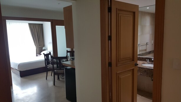 Hotelkamer met een bed, bureau en stoel. Badkamer met wastafel en spiegel.