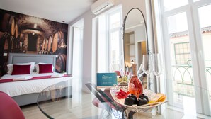 Une chambre d’hôtel avec un lit, une table en verre sur laquelle se trouvent une bouteille et des verres, un panneau d’accueil et une vue sur l’extérieur.