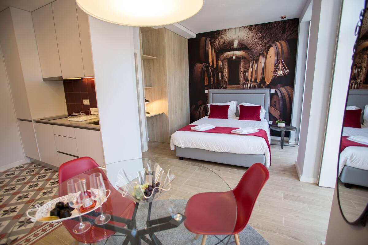 Une chambre d’hôtel comprenant un lit, une table à manger avec des chaises, un coin cuisine et une grande fresque murale.