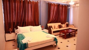A hotel room with a bed, a sofa, a coffee table, and curtains. - Hotel Palace Biskra (Biskra)