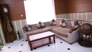 A living room with a sectional sofa, a wooden coffee table, a clock, and a globe. - Hotel Palace Biskra (Biskra)