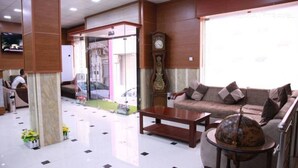 A lobby with a sofa, coffee table, and a clock. - Hotel Palace Biskra (Biskra)