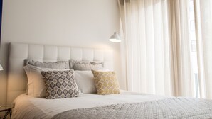 A neatly made bed with a tufted headboard, a bedside lamp, and patterned pillows. - Almada Story Apartments by Porto City Hosts (Porto)