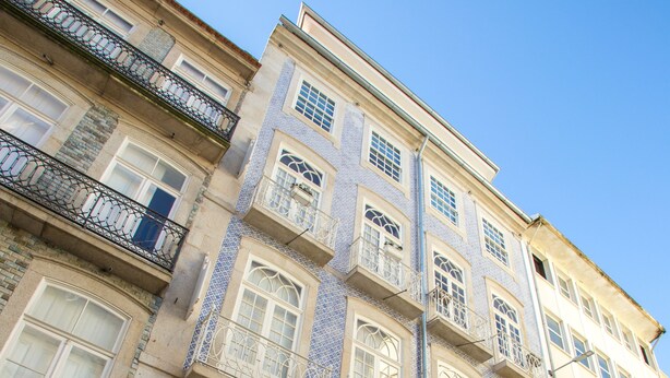 A multi-story building with a mix of architectural styles, including a balcony with ornate metal railings and a shop entrance with a glass door. - Almada Story Apartments by Porto City Hosts (Porto)