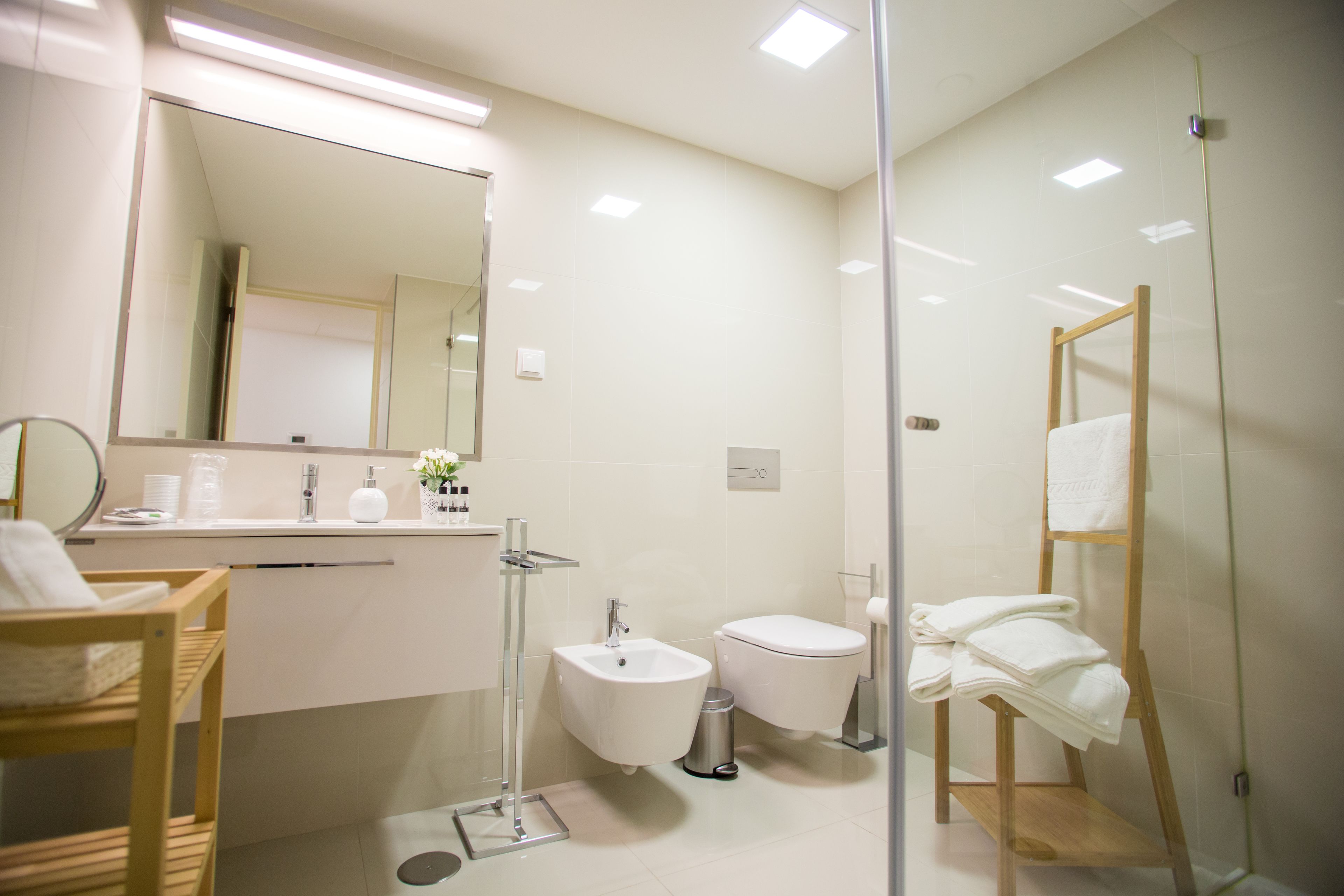 A modern bathroom with a glass shower enclosure, a bidet, a toilet, and a vanity with a mirror.