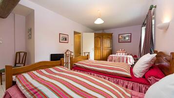 Une chambre avec deux lits, une armoire en bois, une chaise et un luminaire au plafond.