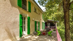 A house with a covered porch, green shutters, and outdoor furniture.