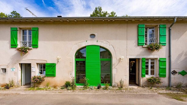 A building with a large arched entrance, green shutters, and flower boxes.