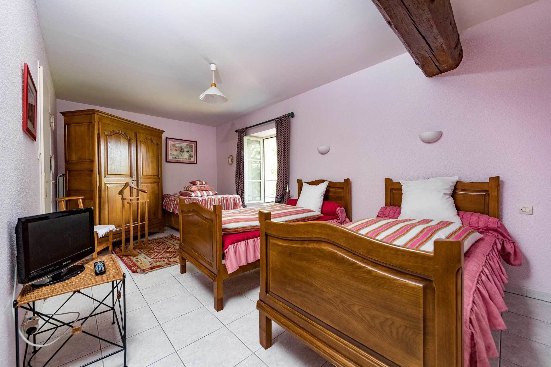 A bedroom with two wooden beds, a television on a stand, and a wooden wardrobe.