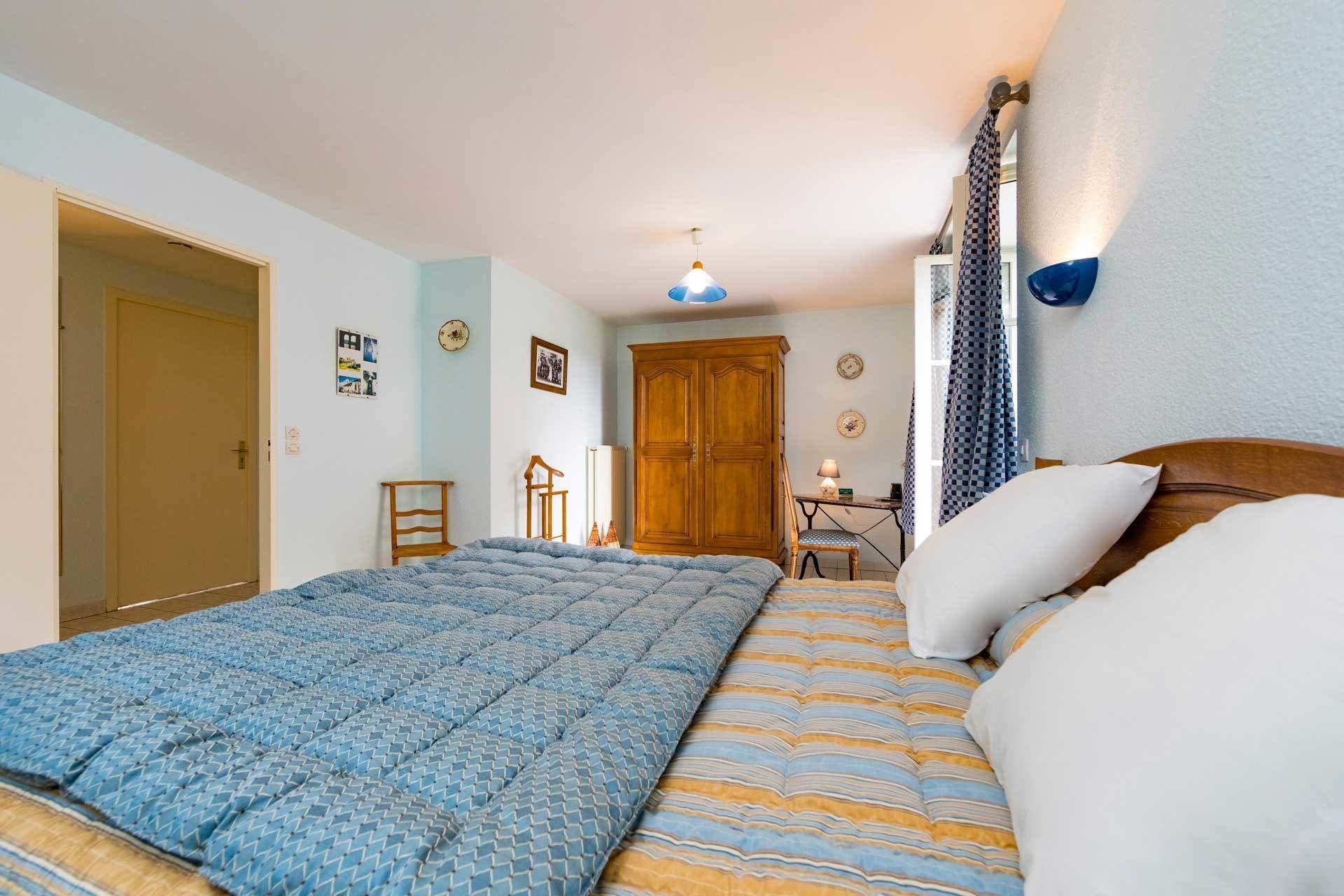 A bedroom with a bed, a wardrobe, a desk, and a chair.