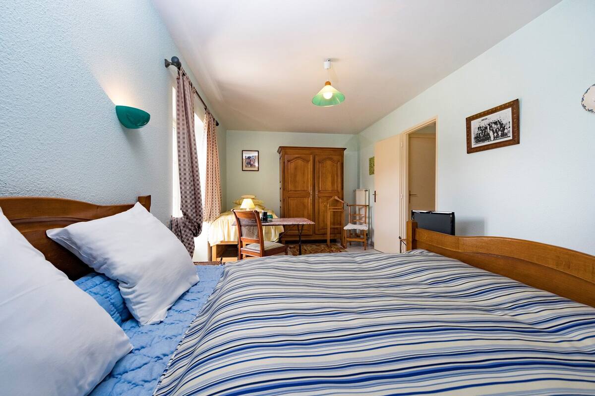 Ein Schlafzimmer mit Bett, Schreibtisch, Stuhl, Kleiderschrank und einem Bild an der Wand.