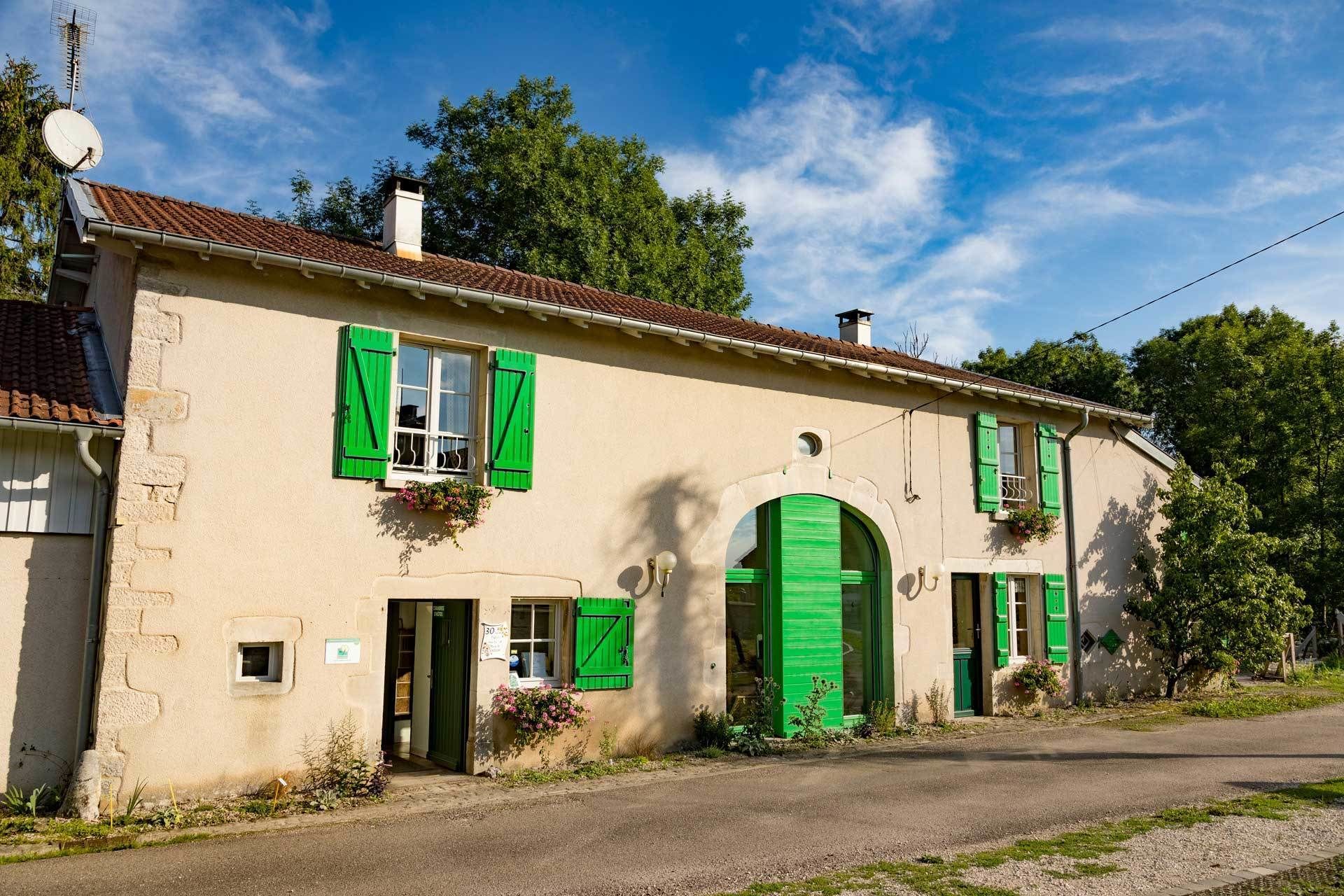 A two-story building with green shutters, a satellite dish, and a small garden area.