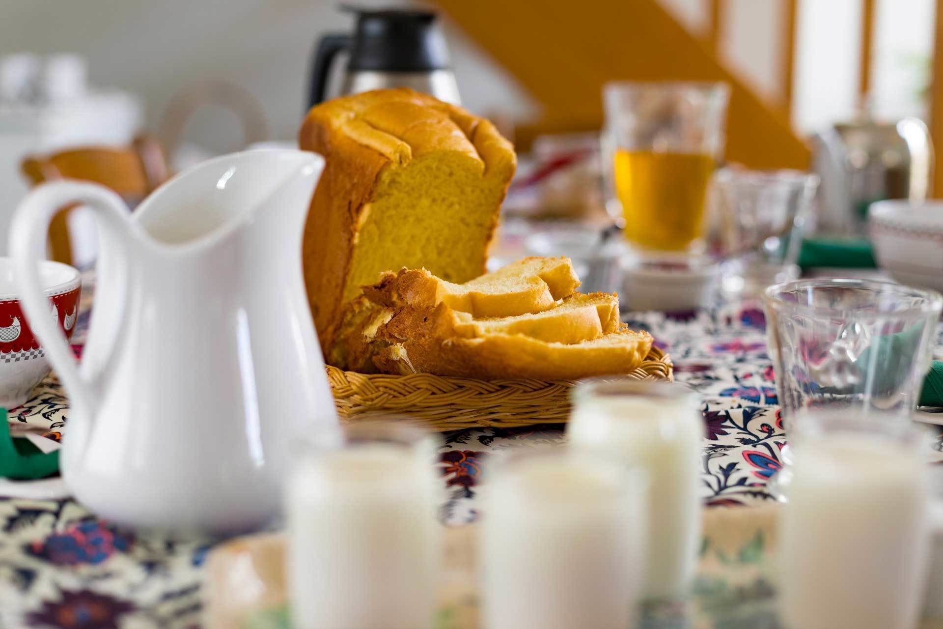 A table with a loaf of bread, a pitcher, and several glasses of milk.