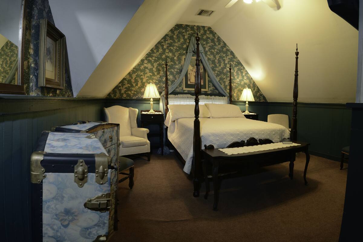 Une chambre à coucher avec un lit à baldaquin, une table de chevet, une chaise et une valise.