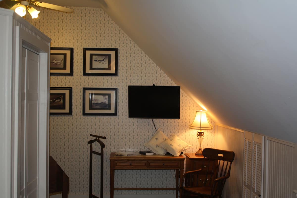 Une pièce comprenant un bureau, une chaise et un téléviseur fixé au mur.