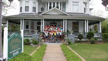 A large house with a porch, a sign for McFarlin House, and a pathway leading to the entrance.