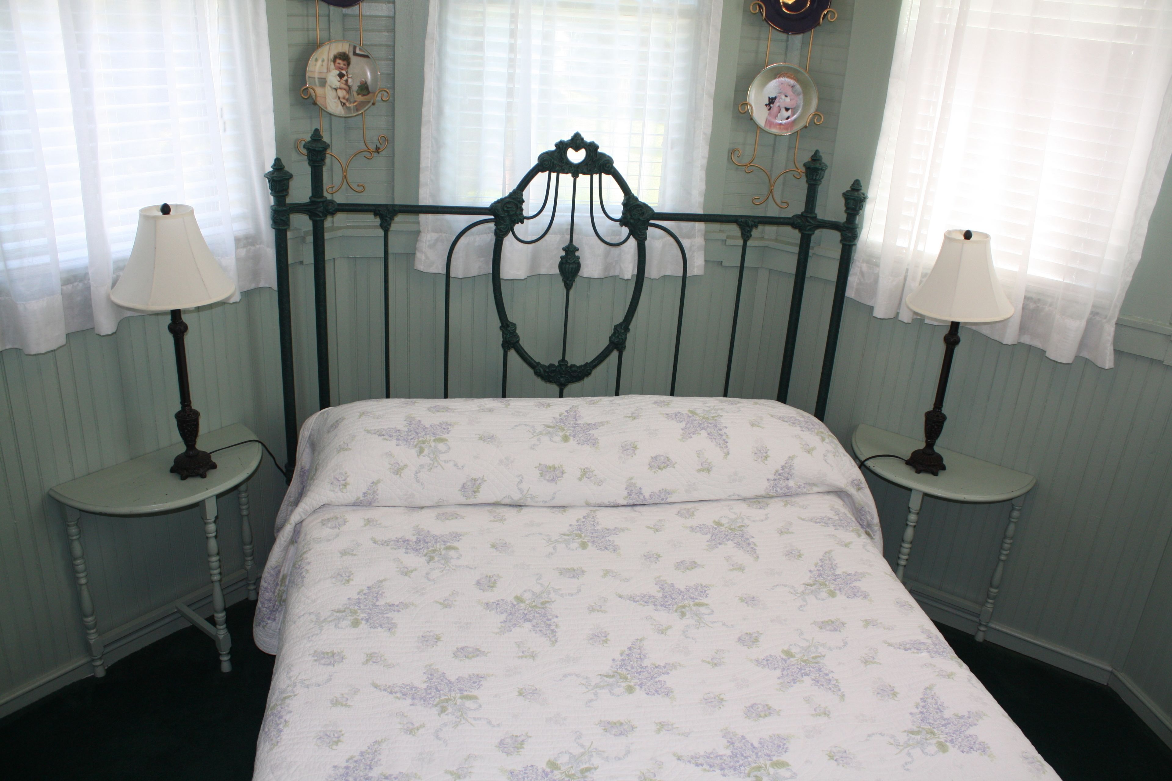A bedroom with a four-poster bed, two bedside tables, and a floral-patterned bedspread.