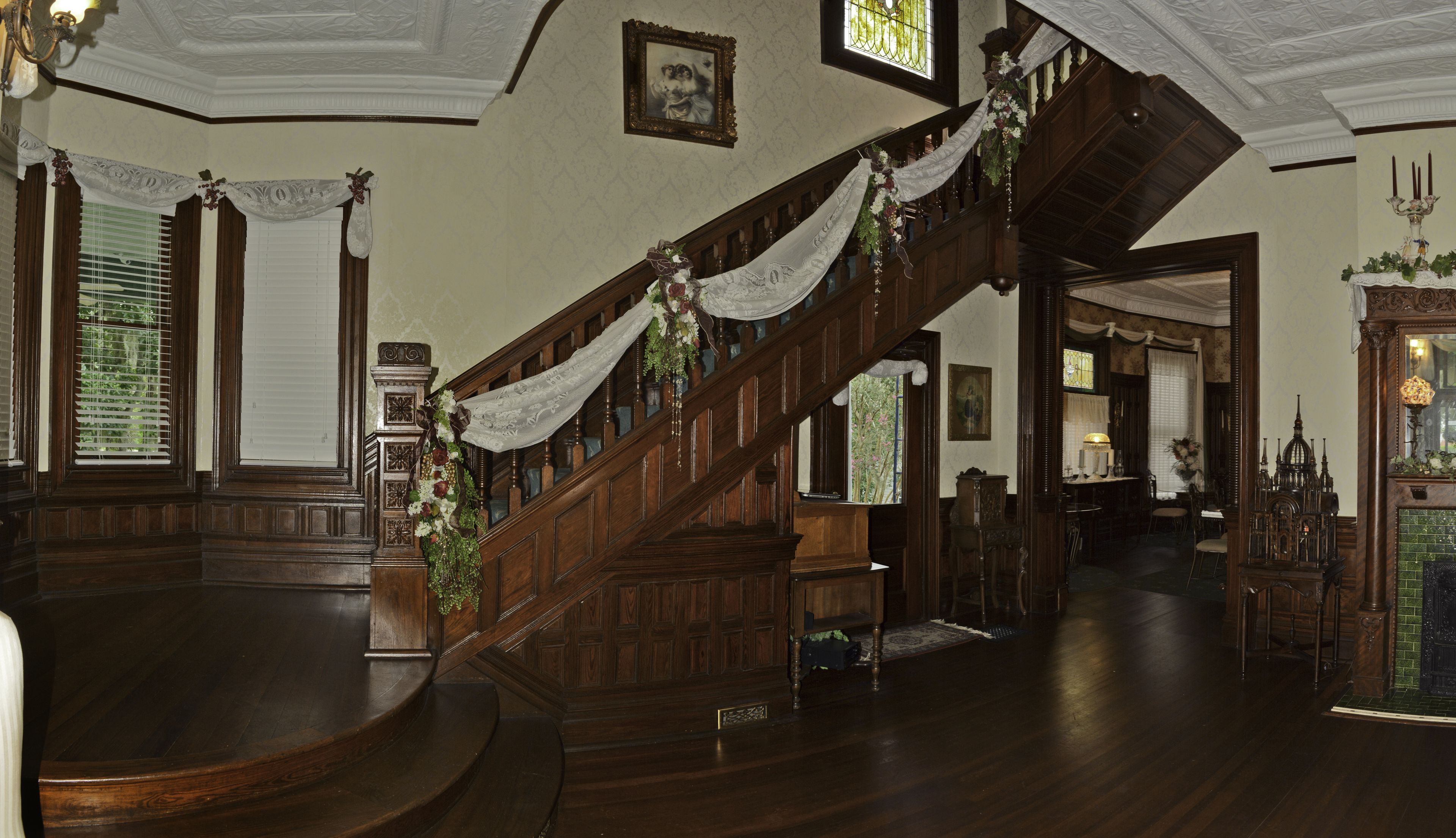 Eine prächtige Treppe mit Blumengesteck, Holzwandverkleidung und einem Chandelier.