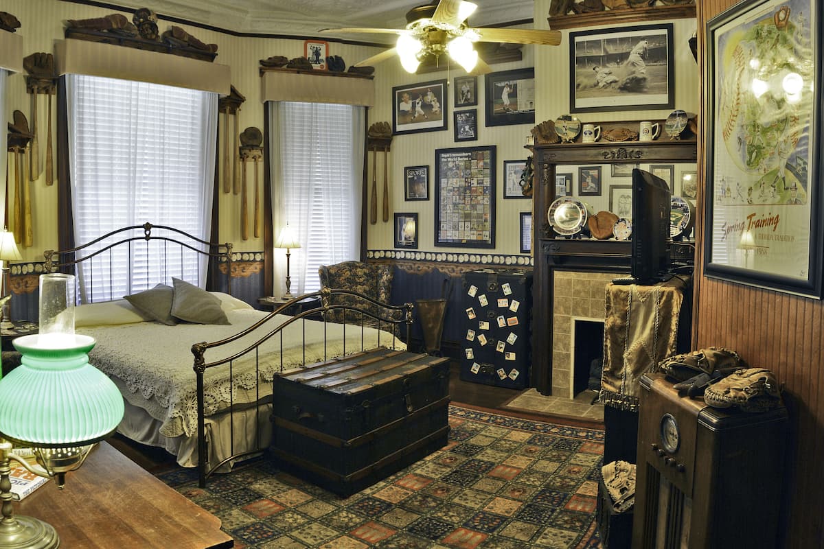 Une chambre à coucher au décor d’époque, avec un lit à baldaquin, une commode en bois et une cheminée.