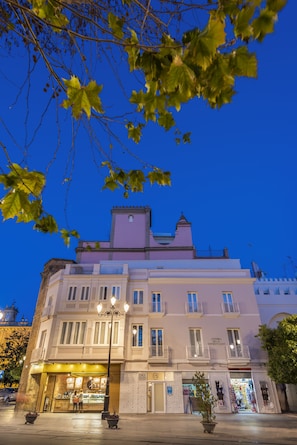 Un edificio storico con facciata rosa, numerosi balconi e un negozio a livello strada.