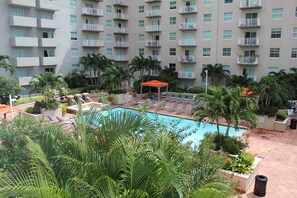 A hotel with a swimming pool surrounded by palm trees and lounge chairs.