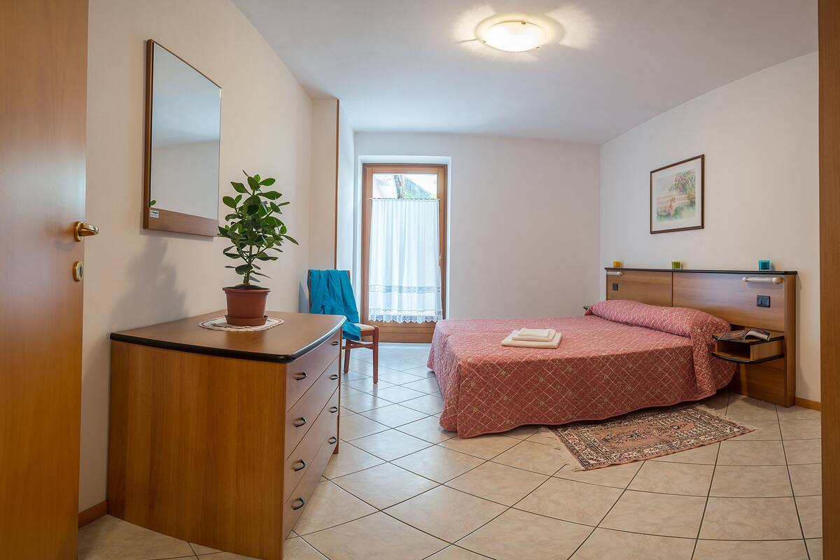 Ein Schlafzimmer mit einem Bett, einem Schminktisch und einer Topfpflanze.