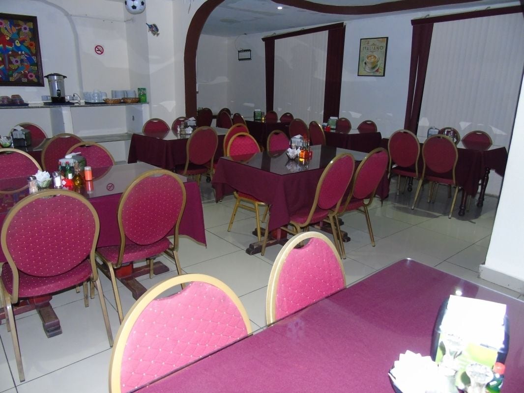 Une salle de conférence avec des tables et des chaises rondes, un espace buffet proposant des plats et des boissons, et un mur orné d’un tableau.