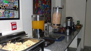 A buffet setup with a variety of food items, a fire safety sign, and a colorful mural on the wall. - Hotel Marparaiso (Panama City)