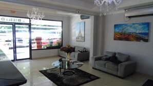 A hotel lobby with a reception desk, a sofa, a coffee table with flowers, a chandelier, and artwork on the walls. - Hotel Marparaiso (Panama City)