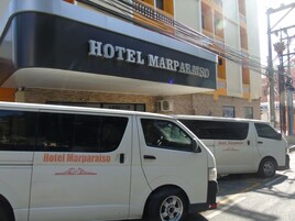 Dos camionetas blancas con la marca 'Hotel Marparaiso' estacionadas frente al hotel.