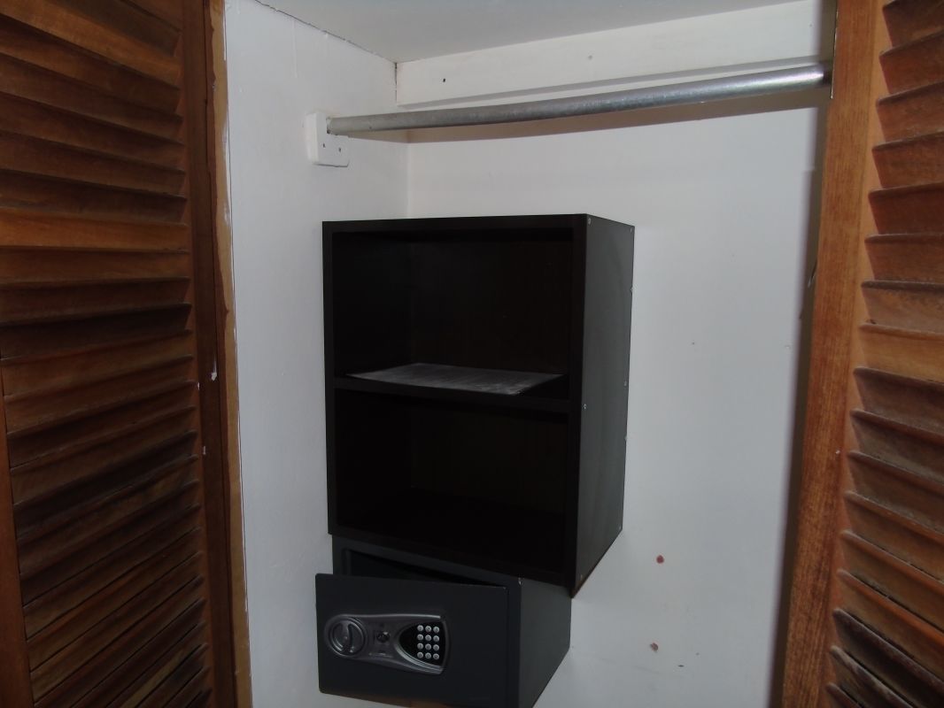 A black electronic device with a keypad and a small display, mounted on a white wall.