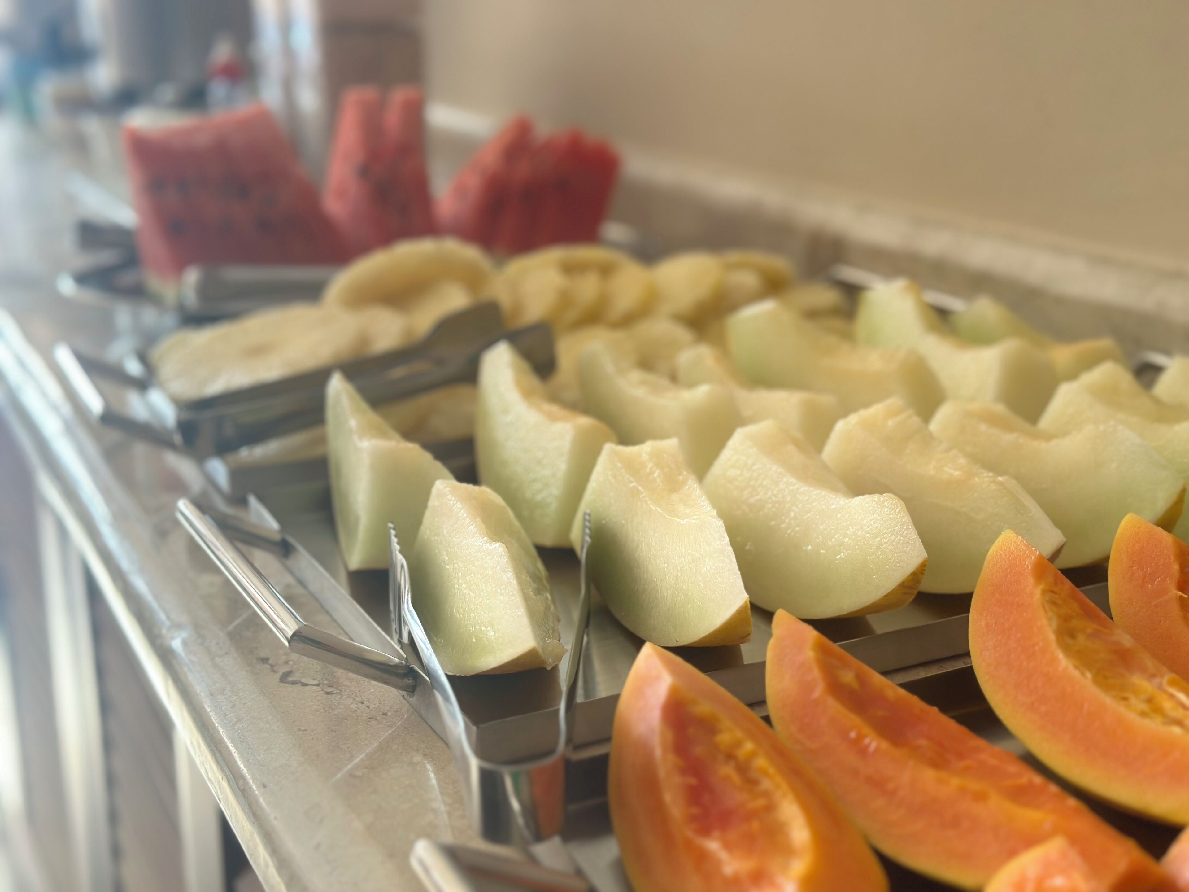 Un buffet proposant une variété de fruits et de légumes, notamment des pastèques et des melons.
